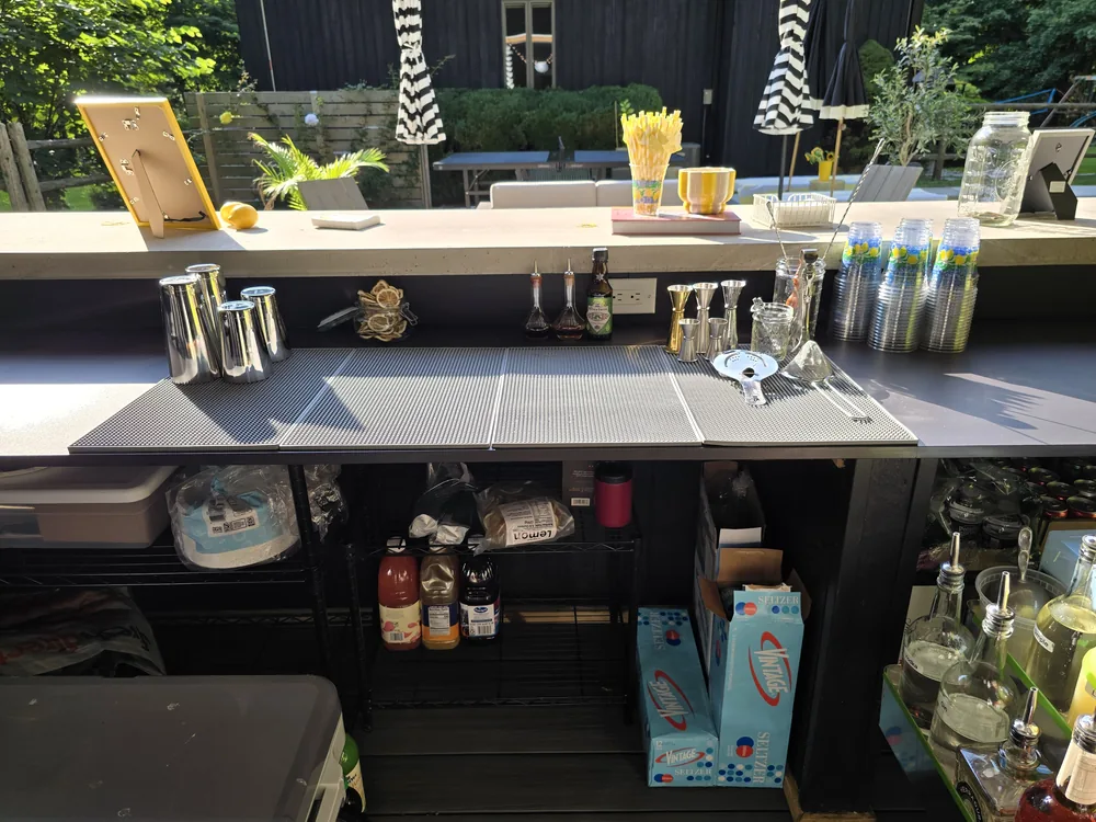 Bartending tool kit laid out on bar mats — shakers, jiggers, and strainers — before service